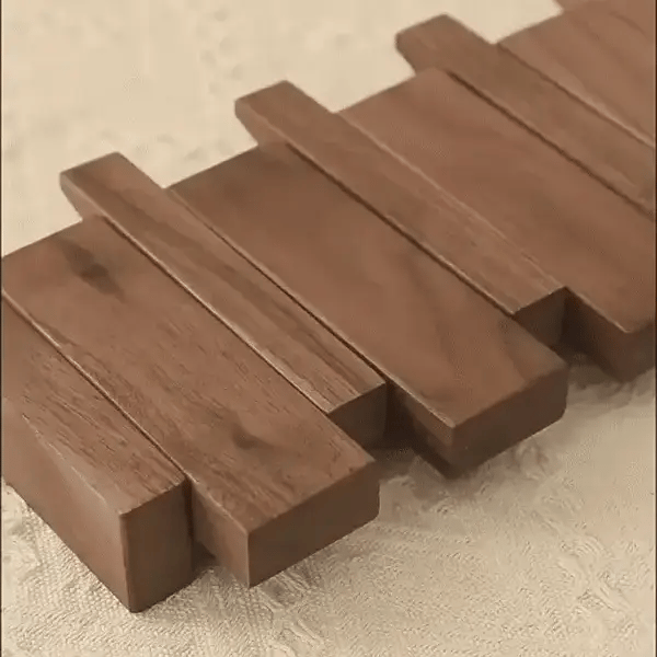 Dřevěný nástěnný věšák s řadou háčků ve tvaru kláves piana
